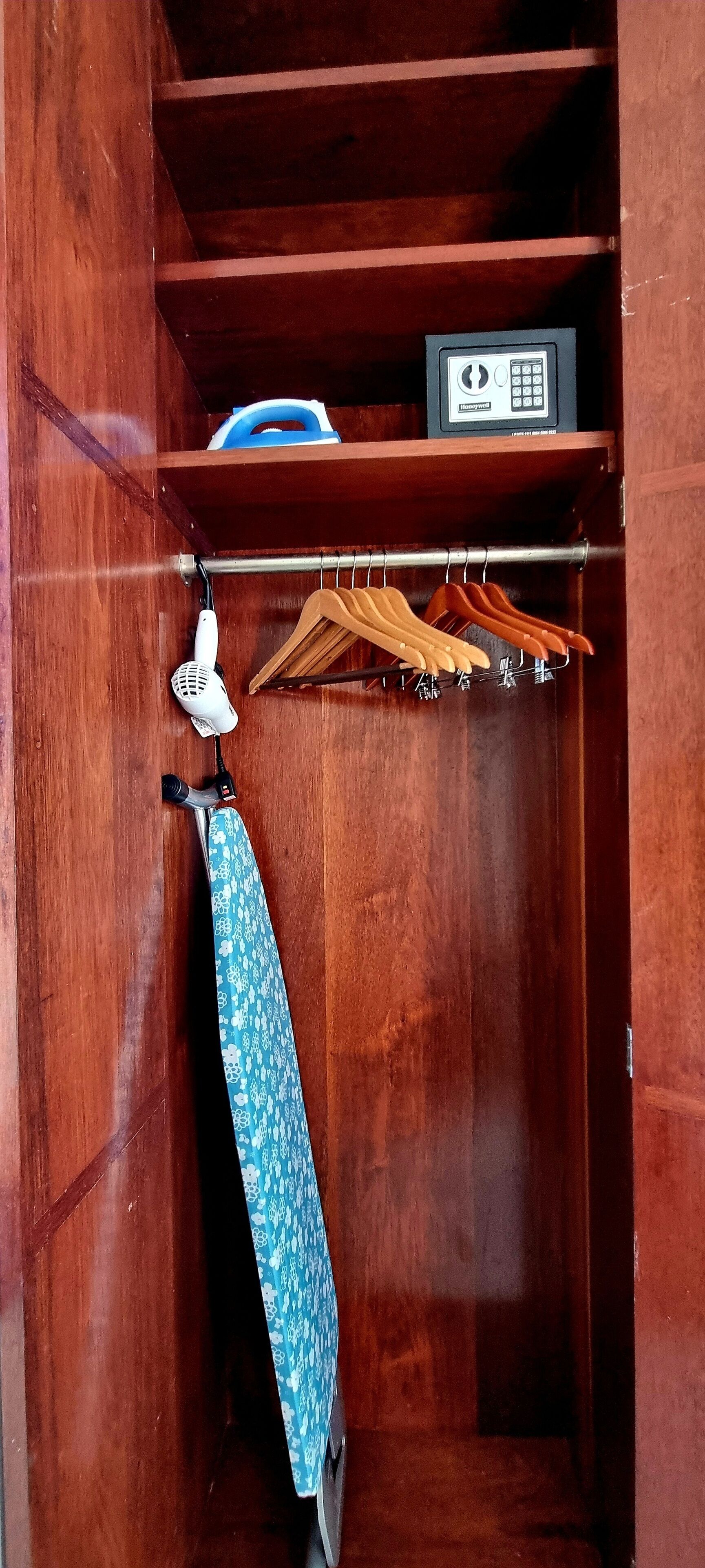 Ein Holzkoffer mit Kleiderstange, ein weißes Gerät und ein blau gemustertes Objekt.