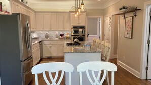 A modern kitchen with white cabinetry, stainless steel appliances, and a central island with bar stools. - Masters Tournament Rental; 4 Bed, 2.5 Bath-4 Bedroom Home in Heart of Evans, GA (Evans)