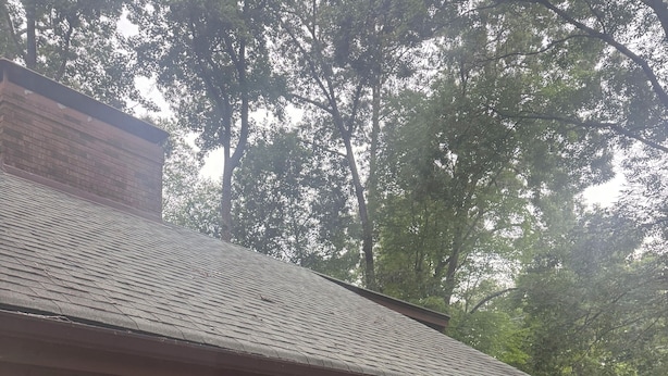 Eine Holzterrasse mit überdachter Veranda, großen Schiebeglasfenstern und einem Backsteinsschornstein.