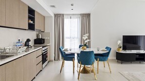Une cuisine moderne dotée d’appareils électroménagers intégrés, un coin repas avec des chaises bleues et un téléviseur à écran plat.
