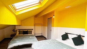 Huoneessa on kaksi sänkyä, kattovalokuvio ja ovi.
