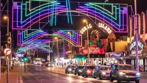 Une rue aux couleurs vives, illuminée par des néons, et dominée par une tour imposante.