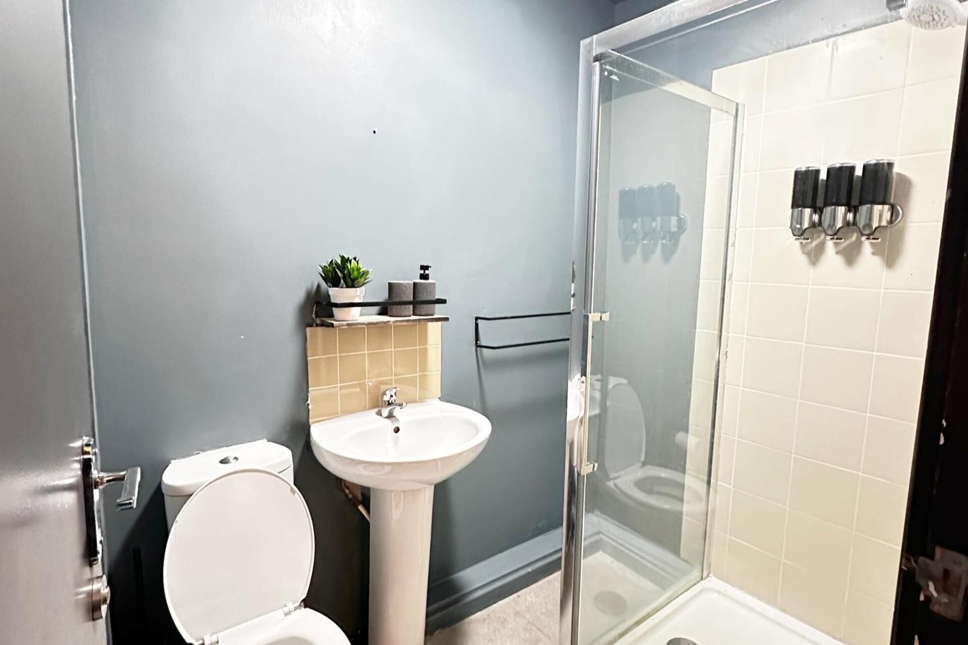 Un baño con inodoro, lavamanos y cabina de ducha de vidrio.