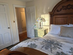 Een slaapkamer met een bed, een nachtkastje, een lamp en een houten hoofdeinde.