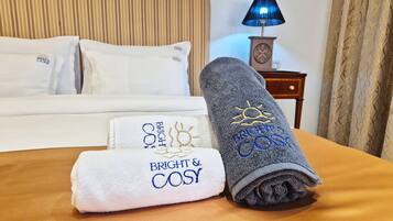 Una cama hecha con dos toallas, una blanca y otra gris, ambas con detalles bordados.