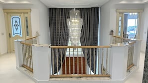 Stunning entrance hall with a grand staircase, ornate chandelier, and elegant railings.