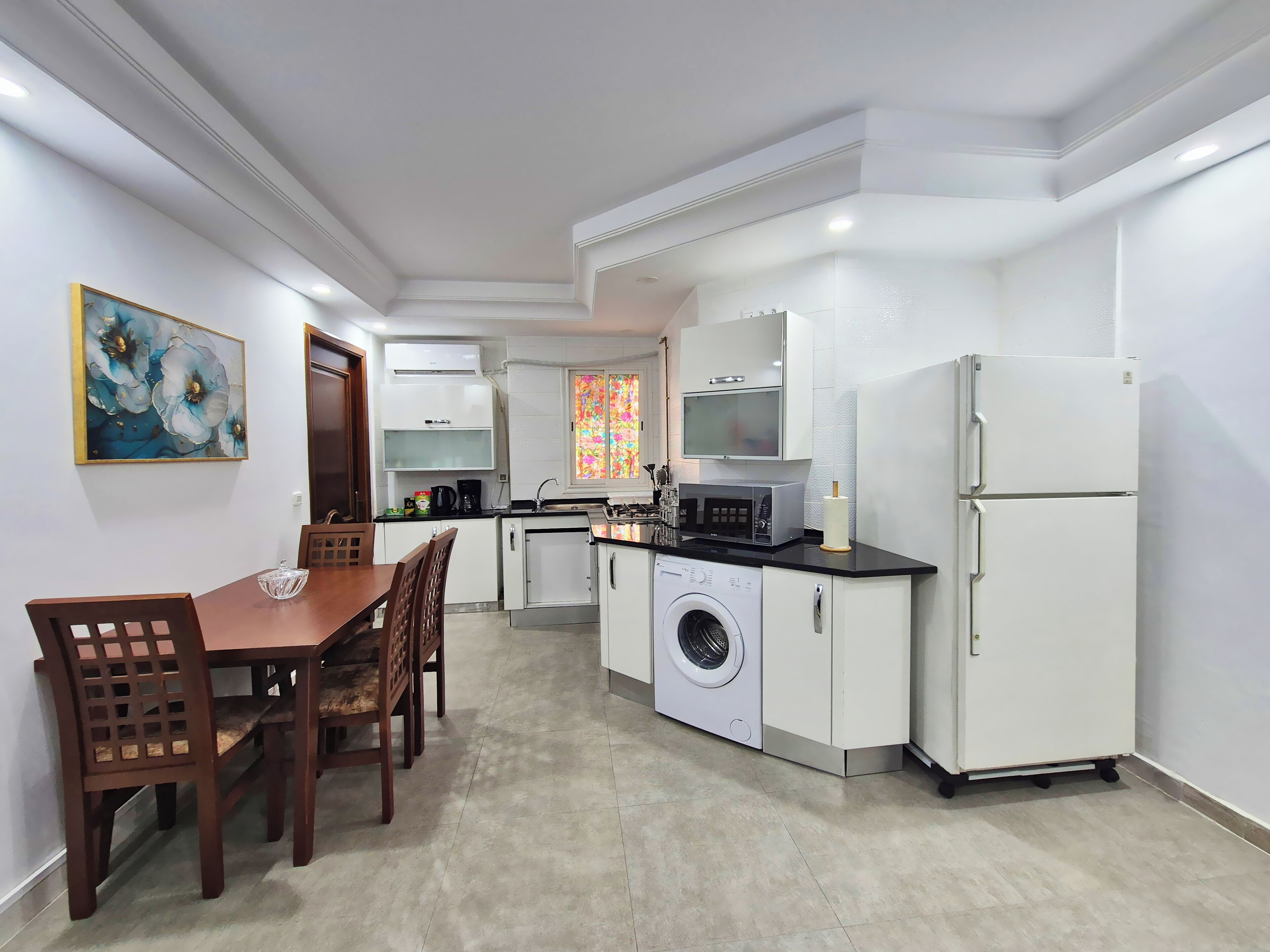 A compact kitchen with a washing machine, a microwave, and a refrigerator.