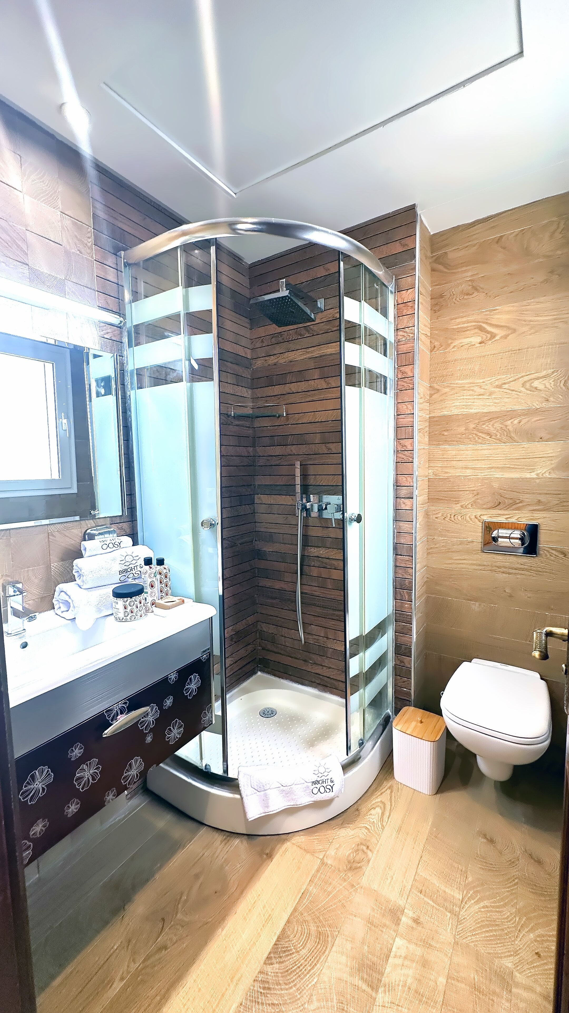 A modern bathroom with a glass-enclosed shower, a vanity with a mirror, and a toilet.