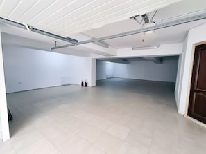 Spacious interior with high ceiling, metal beam structure, and light-colored floor.