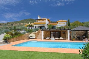 A villa with a swimming pool, outdoor seating, and a stone wall. - Andalusian family retreat with pool, padel court & near El Torcal de Antequera (Antequera)
