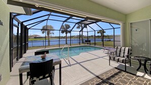 Un'area esterna coperta con piscina, posti a sedere e vista sul lago.