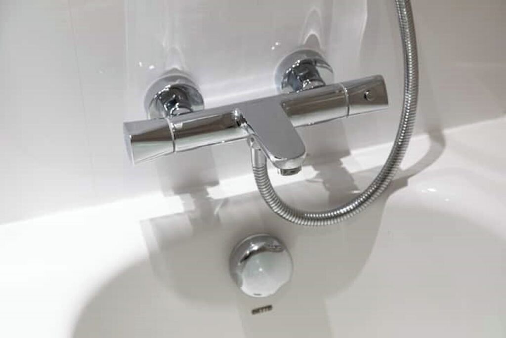A chrome shower control with a flexible hose.