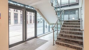Una entrada de hotel moderna con puerta de vidrio, una escalera y vista a la calle.