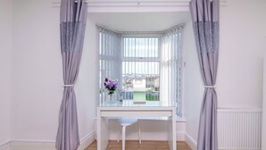 A corner room with a bay window, a white desk, a chair, and a view of the city. - 3BDR Home in Central Holyhead (Holyhead)