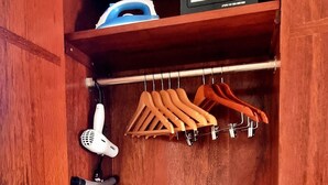 A wooden closet with a hanging iron, a hairdryer, and a small appliance on the top shelf. - Cozy 1-bedroom apartment in charming Long Bay Hills with WiFi, AC (Long Bay Hills)