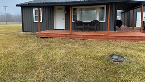 A small, single-story building with a porch, two chairs, and a table. - Cozy 2-bedroom cabin with WiFi, AC in tranquil Moravia (Moravia)