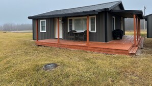 A small, single-story house with a porch and a covered outdoor seating area. - Cozy 2-bedroom cabin with WiFi, AC in tranquil Moravia (Moravia)