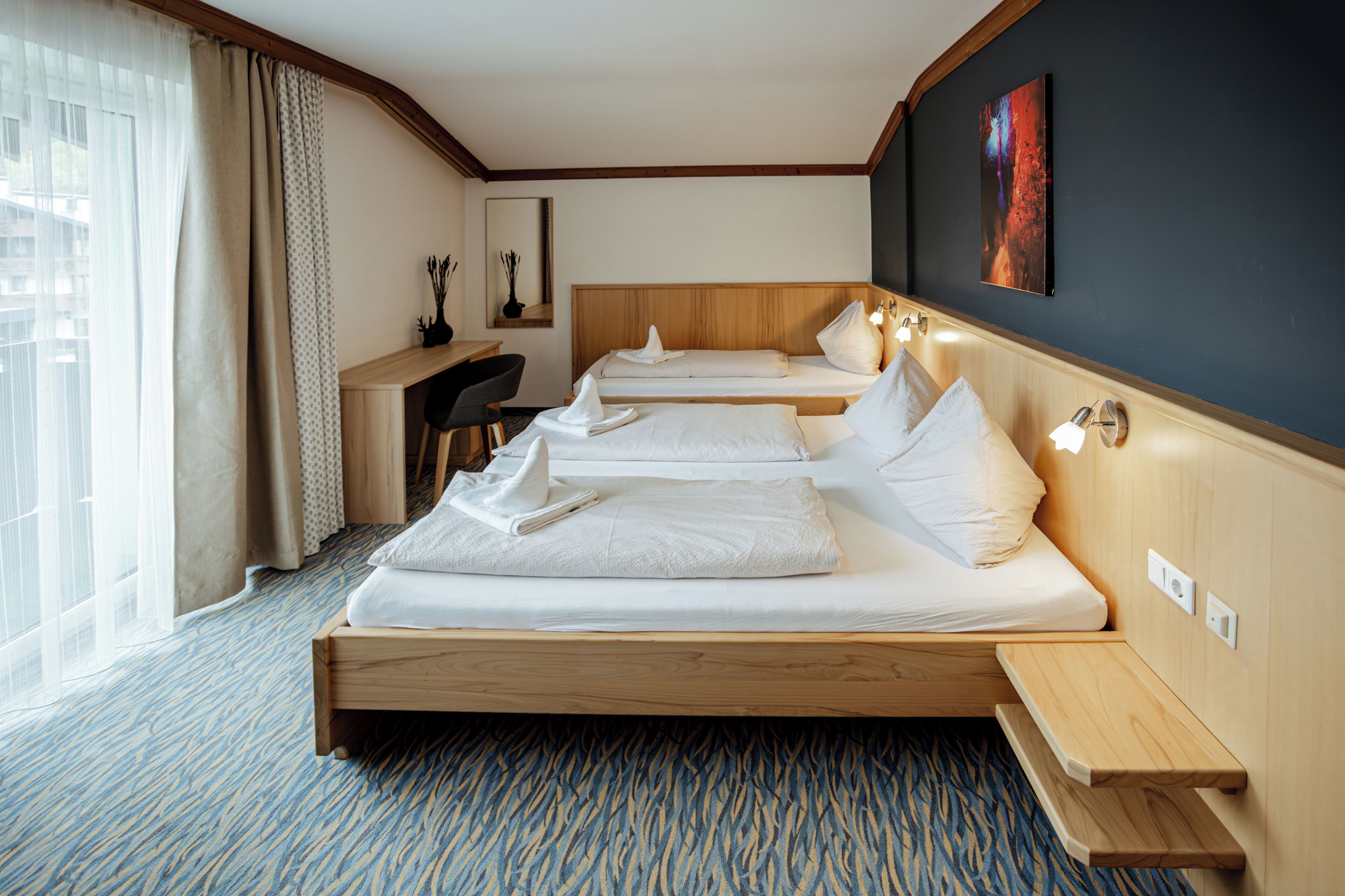 A hotel room with two beds, a desk, and a chair.