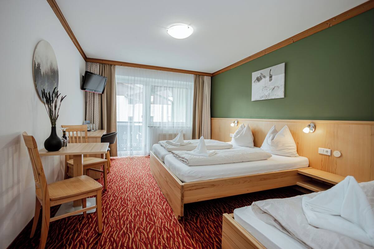 Una habitación de hotel con cama, escritorio, silla, televisión y un cuadro en la pared.