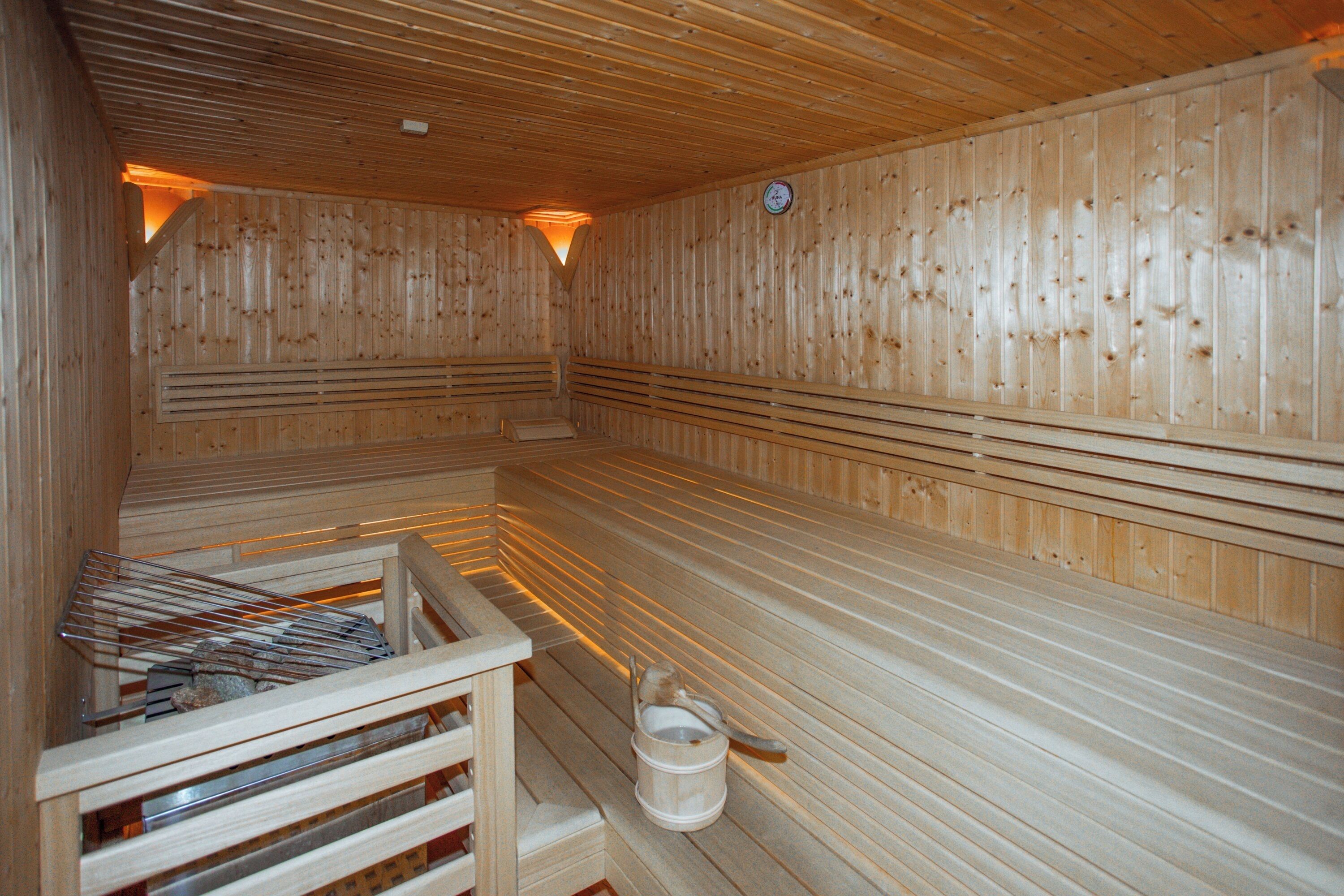 A sauna with wooden benches and a wooden bucket.