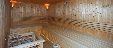 A sauna with wooden benches and a wooden bucket.