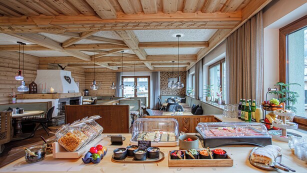 Un espace buffet proposant une variété de plats, avec des poutres en bois au plafond et différents types de sièges.