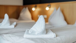Une chambre d’hôtel avec des lits bien faits, chacun agrémenté d’un oreiller et d’une serviette pliée.