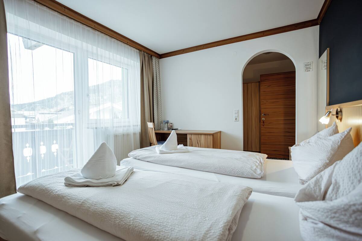 Una habitación de hotel con dos camas, un escritorio y vistas al exterior.