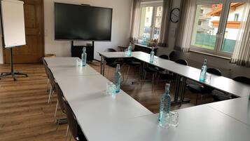 Ein Konferenzraum mit langem Tisch, Stühlen, einer Projektionsleinwand und einer Uhr an der Wand.