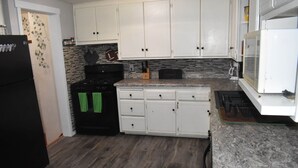 A kitchen with white cabinets, a black refrigerator, a stove, and a microwave.
