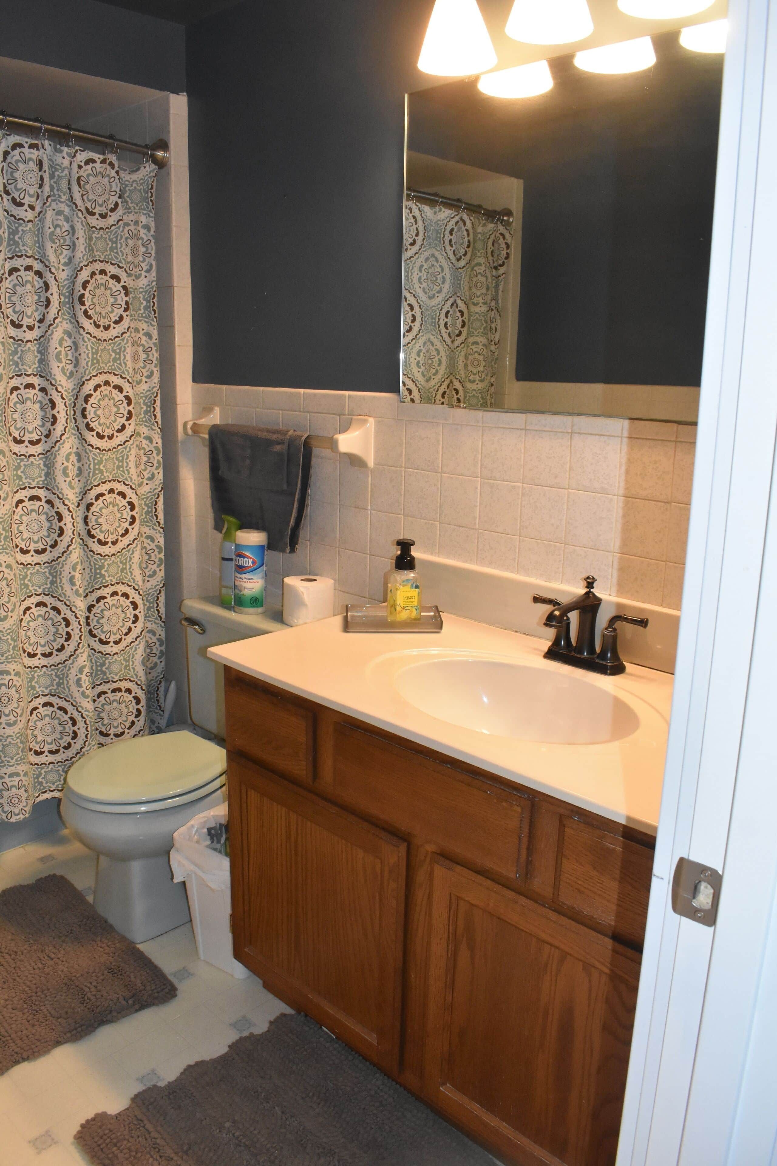 A bathroom with a toilet, sink, mirror, and shower curtain.