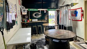 A room with a table, chairs, a bar area, and a sign indicating 'Spotted Cow.'