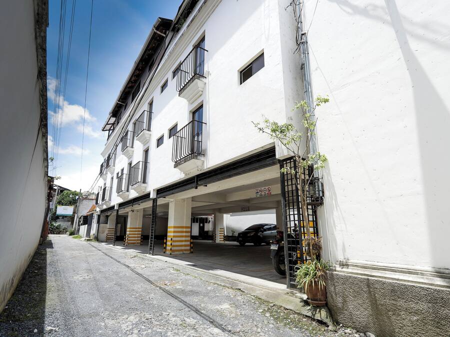 Eine schmale Straße mit einem weißen Gebäude, das Balkone und eine Tiefgarage hat.