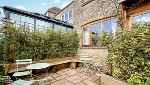 A stone building with a patio, a table, and chairs.