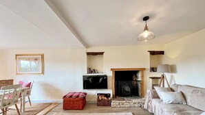 A living room with a fireplace, a sofa, a television, and a dining area with chairs and a table.