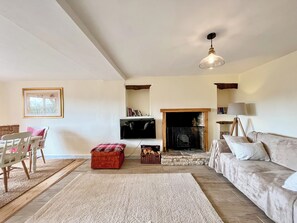 Ein Wohnzimmer mit Kamin, einer Couch, einem Fernseher und einem Essbereich mit Stühlen und einem Tisch.