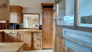 A wooden kitchen with cabinets, a microwave, and a sign indicating '44 Drovers Cottage.'