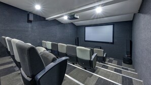 Una sala de cine moderna con filas de asientos, una pantalla grande y un proyector.