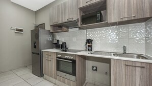 Una cocina moderna con armarios de madera, un refrigerador de acero inoxidable, un horno, un microondas y un lavamanos.