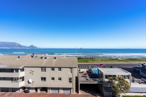 A coastal building with a flat roof, satellite dish, and a view of the ocean.