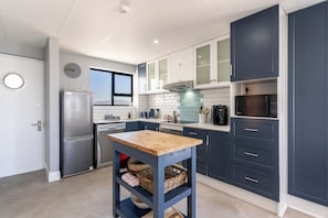 Eine moderne Küche mit eingebautem Backofen, Mikrowelle und einem Holztisch mit Körben darunter.