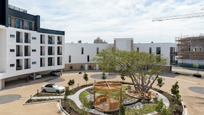 A modern building with a courtyard featuring a wooden gazebo, seating, and landscaping. - On Park | Modern Century City Studio (Cape Town)