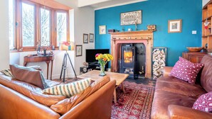 A cozy living room with a fireplace, leather sofas, and a blue accent wall. - 3 bedroom accommodation in Castle Martin, near Pembroke (Castle Martin, near Pembroke)
