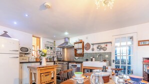 A modern kitchen with a dining area, equipped with a refrigerator, oven, microwave, and various kitchen utensils. - 3 bedroom accommodation in Castle Martin, near Pembroke (Castle Martin, near Pembroke)