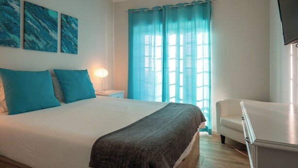Une chambre à coucher avec un lit, une table de chevet, une chaise et un téléviseur.