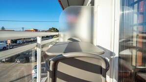 Ein Balkon mit Tisch und Stühlen, mit Blick auf einen Parkplatz und Gebäude.