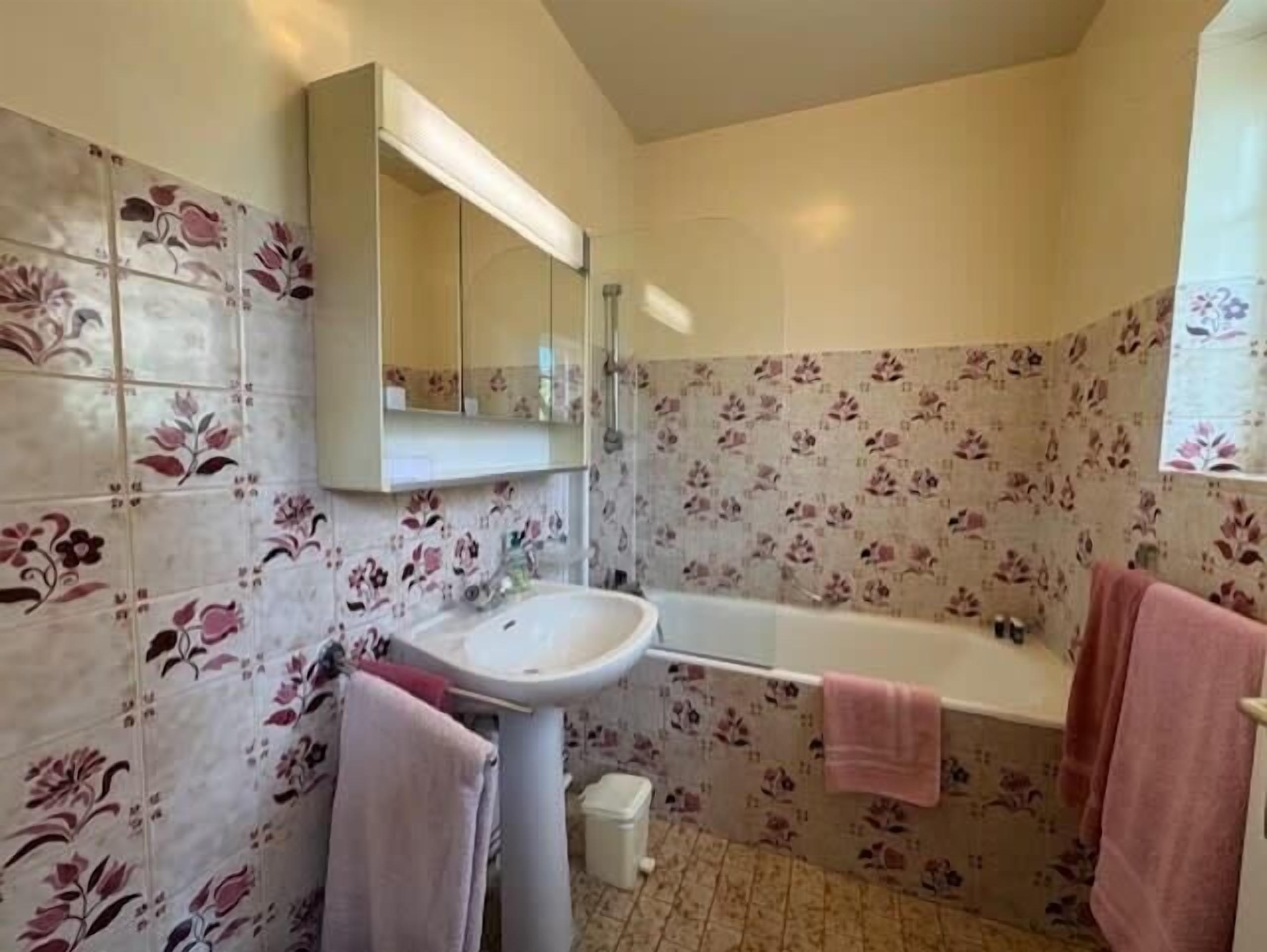 A bathroom with a sink, mirror, and bathtub.