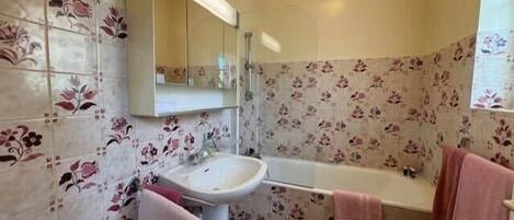 A bathroom with a sink, mirror, and bathtub.