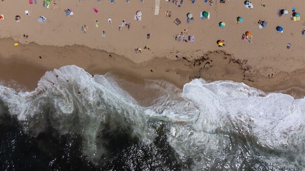 A beach with waves crashing onto the shore and people scattered across the sand.