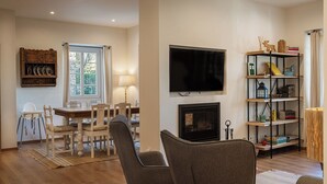 A living room with a fireplace, a television, a dining area with chairs, and a bookshelf. - Close to all the magical places in Sintra. (Sintra)